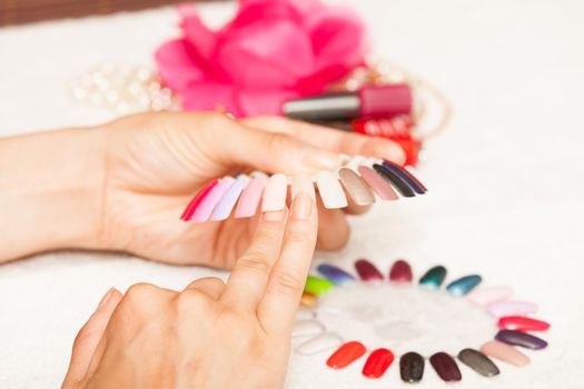 Hands of a woman who chooses the color of her nail polish