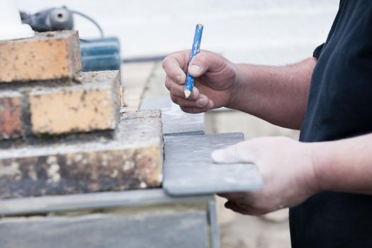 the tiler measures and puts marks to cut and lay a tile