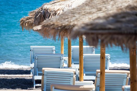 beach with umbrellas and deck chairs in Santorini