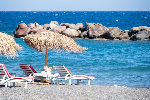 beach with umbrellas and deck chairs in Santorini