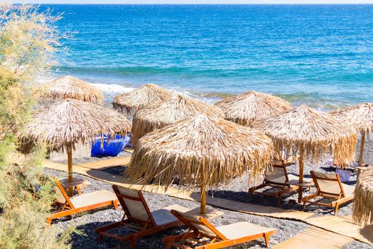 beach with umbrellas and deck chairs in Santorini