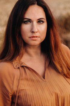 portrait of a Girl in a orange long dress with long hair in nature in the evening