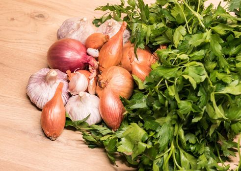 garlic onion shallot parsley on a wooden board