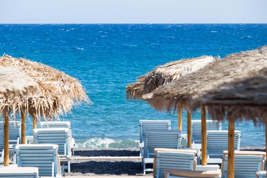 beach with umbrellas and deck chairs in Santorini