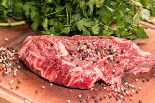 steak of beef on a wooden board with spices and parsley