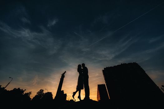 a young couple embraces in the city at a beautiful sunset, urban style.