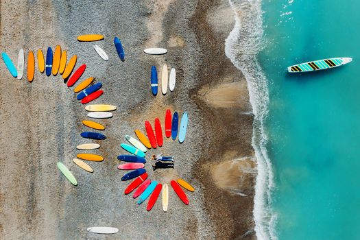 a beautiful couple is lying on the beach of France next to surfboards, shooting from a quadcopter, a lot of surfboards are unusually lying on the beach.