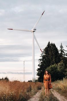 portrait of a Girl in a orange long dress with long hair in nature in the evening