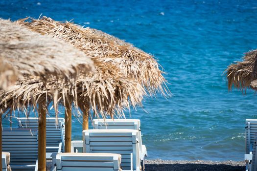 beach with umbrellas and deck chairs in Santorini