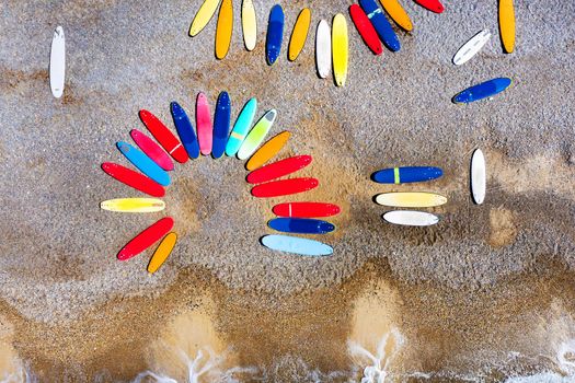 Top view of colored surfboards lying chaotically on a shingle beach in France.