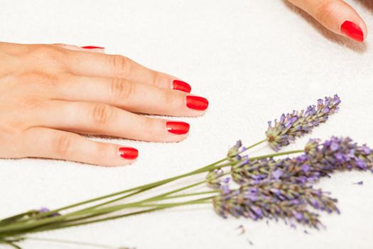 Hands of a woman with red nail polish posed by an esthetician