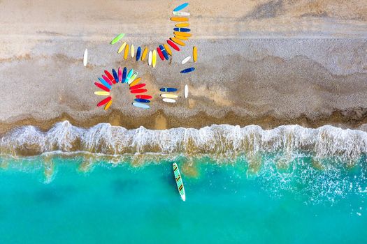 Top view of colored surfboards lying chaotically on a shingle beach in France.