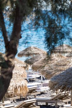 beach with umbrellas and deck chairs in Santorini