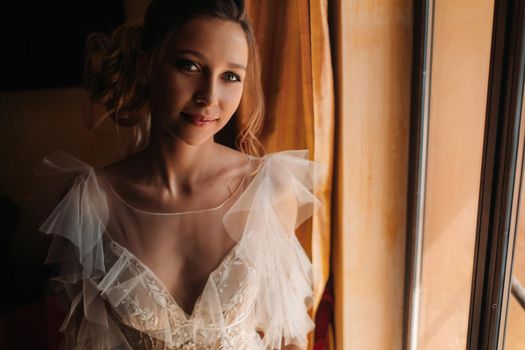 pretty blonde bride with nicea beautiful bride with pleasant features in a wedding dress poses in the interior of the room. Portrait of the bride in Provence. France.