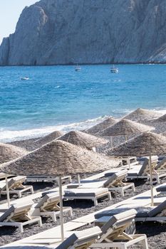 beach with umbrellas and deck chairs in Santorini