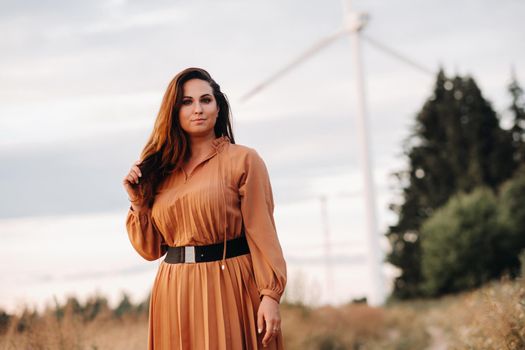 portrait of a Girl in a orange long dress with long hair in nature in the evening