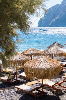 beach with umbrellas and deck chairs in Santorini