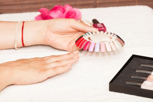 Hands of a woman who chooses the color of her nail polish