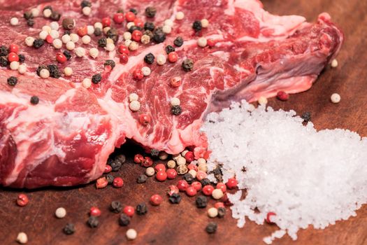 steak of beef on a wooden board with spices pepper parsley salt onions shallots garlic