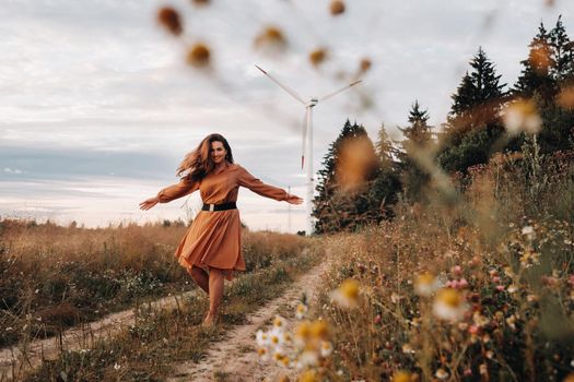 portrait of a Girl in a orange long dress with long hair in nature in the evening