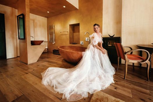 pretty blonde bride with nicea beautiful bride with pleasant features in a wedding dress poses in the interior of the room. Portrait of the bride in Provence. France.