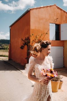 a bride with nice features in a wedding dress with a creative bouquet. Portrait of the bride in Provence. France.