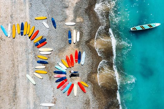 a beautiful couple is lying on the beach of France next to surfboards, shooting from a quadcopter, a lot of surfboards are unusually lying on the beach.