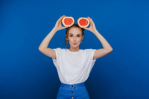 Surprised, the laughing girl holds the grapefruit like ears. Vegan lifestyle. Smiling woman , eating concept.Diet organic , weight loss and healthy food. Smoothies and fresh juice