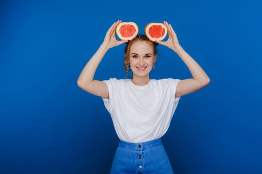 Surprised, the laughing girl holds the grapefruit like ears. Vegan lifestyle. Smiling woman , eating concept.Diet organic , weight loss and healthy food. Smoothies and fresh juice