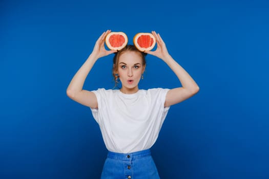 Surprised, the laughing girl holds the grapefruit like ears. Vegan lifestyle. Smiling woman , eating concept.Diet organic , weight loss and healthy food. Smoothies and fresh juice
