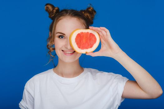 Surprised, the laughing girl holds the grapefruit like ears. Vegan lifestyle. Smiling woman , eating concept.Diet organic , weight loss and healthy food. Smoothies and fresh juice