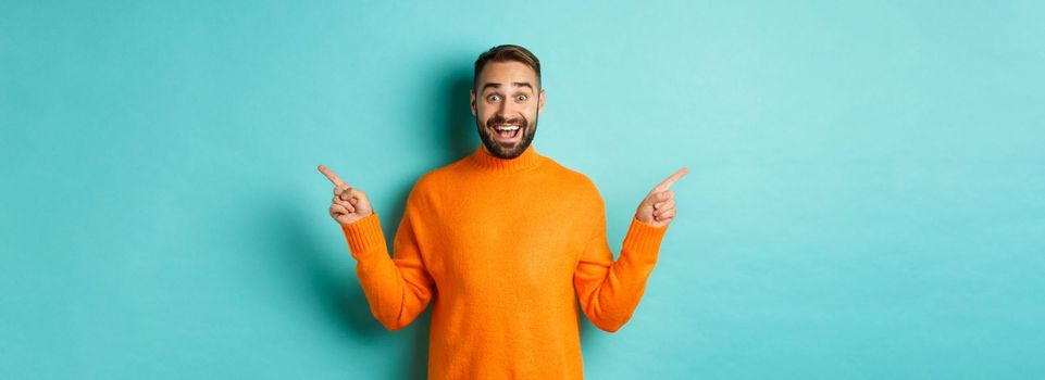 Shopping and advertisement concept. Excited man buyer pointing fingers sideways, showing two choices products, left and right banners, standing over light blue background.