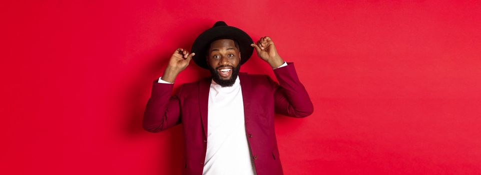 Christmas shopping and people concept. Happy Black man having fun on party, smiling happy at camera, red background.