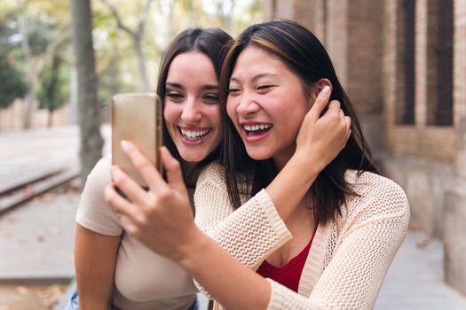 two young women having fun recording a video for social media with their mobile phone, concept of technology of communication and social media