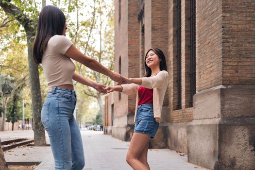 two young women have a good time spinning holding hands during their date, concept of friendship and love between people of the same sex