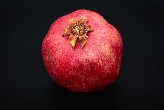 Close-up photo of pomegranate on black background, detailed image of pomegranate fruit