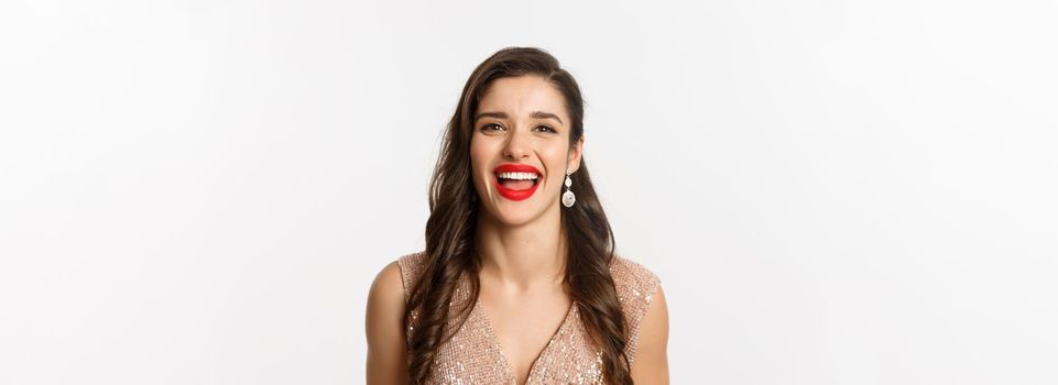 Concept of New Year celebration and winter holidays. Close-up of happy young woman dressed for party, laughing and smiling at camera, white background.
