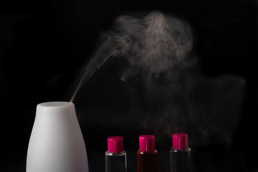 aroma humidifier steaming with scent pots isolated on a black background