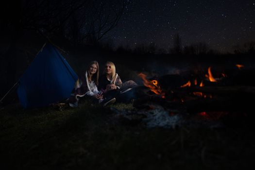 The family, mother and daughter, for the weekend went out into the countryside for a picnic, sit by the fire in the wild with a tent, fry potatoes, drink hot tea. High quality photo