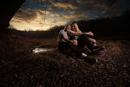 The family, mother and daughter, for the weekend went out into the countryside for a picnic, sit by the fire in the wild with a tent, fry potatoes, drink hot tea. High quality photo
