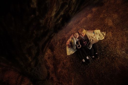 The family, mother and daughter, for the weekend went out into the countryside for a picnic, sit by the fire in the wild with a tent, fry potatoes, drink hot tea. High quality photo