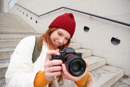 Portrait of female photographer walking around city with professional camera, taking pictures capturing urban shots, photographing outdoors.