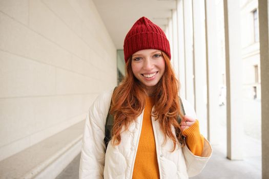 Young tourist, happy girl walking around european city with backpack, student goes to university, goes somewhere in town. Copy space