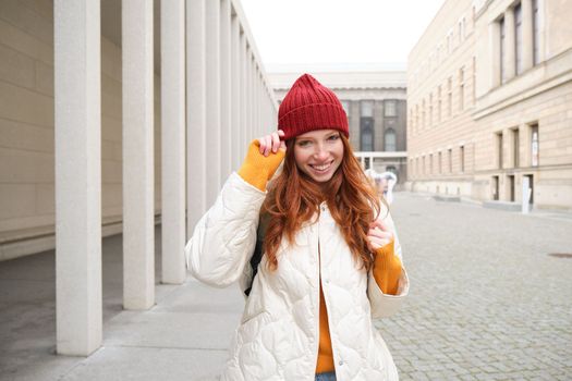 Happy redhead girl, tourist going around town, exploring sighsteeing places in city, backpacking around europe, enjoys travelling.