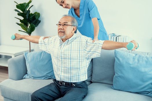 Contented senior patient doing physical therapy with the help of his caregiver. Senior physical therapy, physiotherapy treatment, nursing home for the elderly