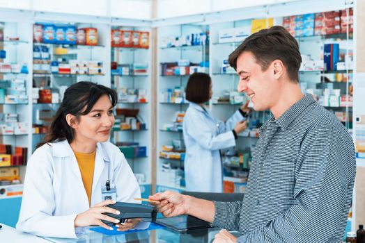 Payment by credit card with payment terminal in qualified drugstore. Modern financial payment of electric money. Caucasian customer purchase medication in pharmacy with prescription from pharmacist.