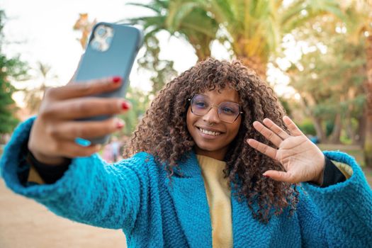 Attractive black woman smiling taking selfie with smart phone. Positive cheerful African female sharing in social media app. High quality photo.