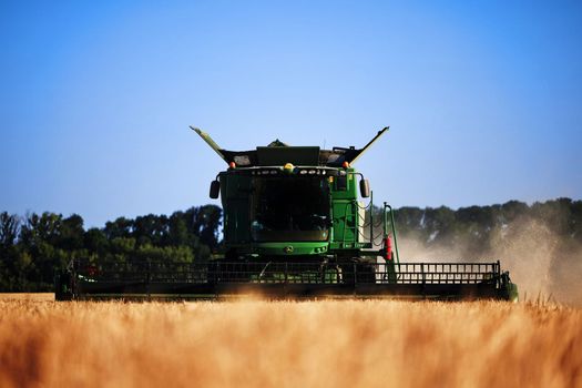 John Deere harvester works in the field. Combine Harvesting Wheat. Field field of cereals during harvesting. Modern equipment works. 07.07.22, Rostov region, Russia.