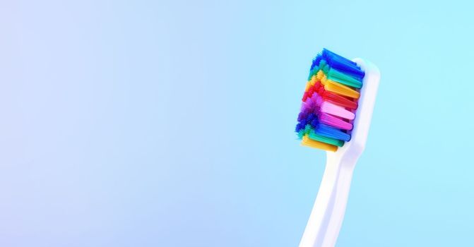 White toothbrush with multicolored bristles. Bristles in all colors of the rainbow. Rainbow toothbrush with white knob. Fashionable oral care