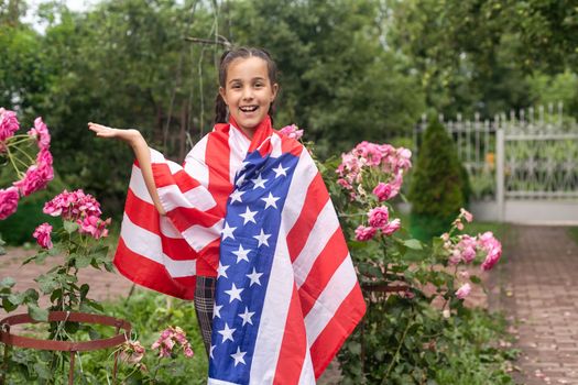 Close-up portrait of a young girl holding the American flag at the park. High quality photo